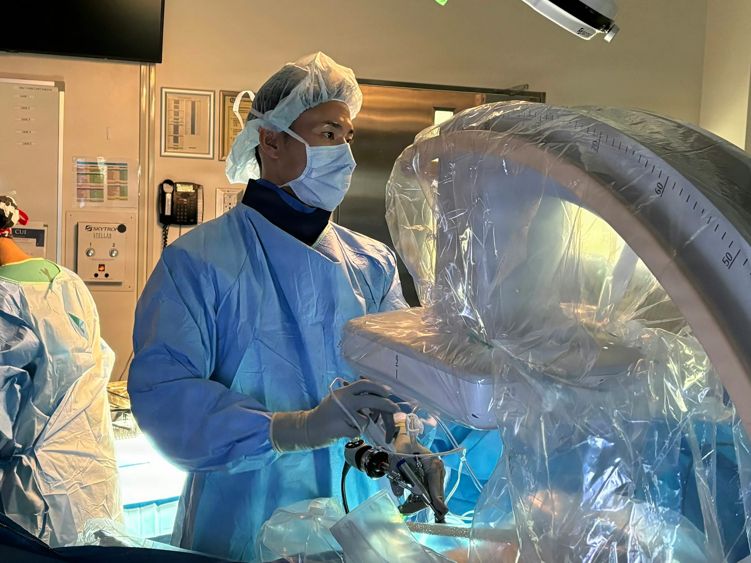 A surgeon operating robotic surgical equipment in an operating room