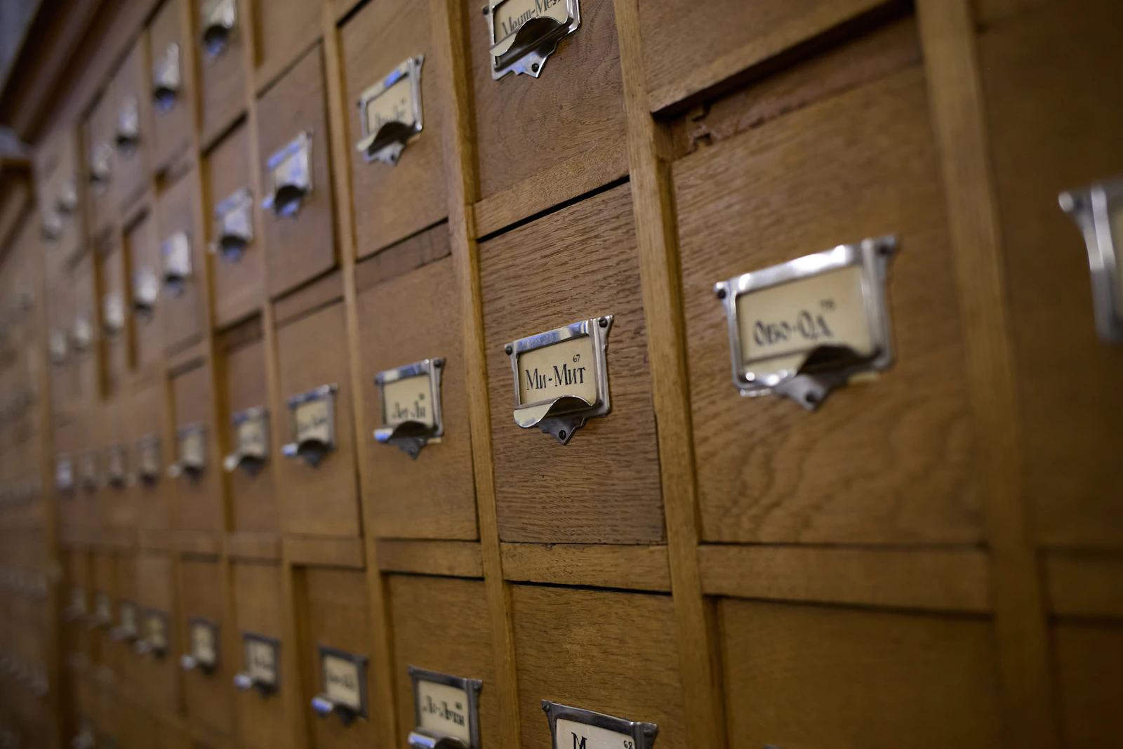 Rows of wooden library card catalog drawers with metal label holders